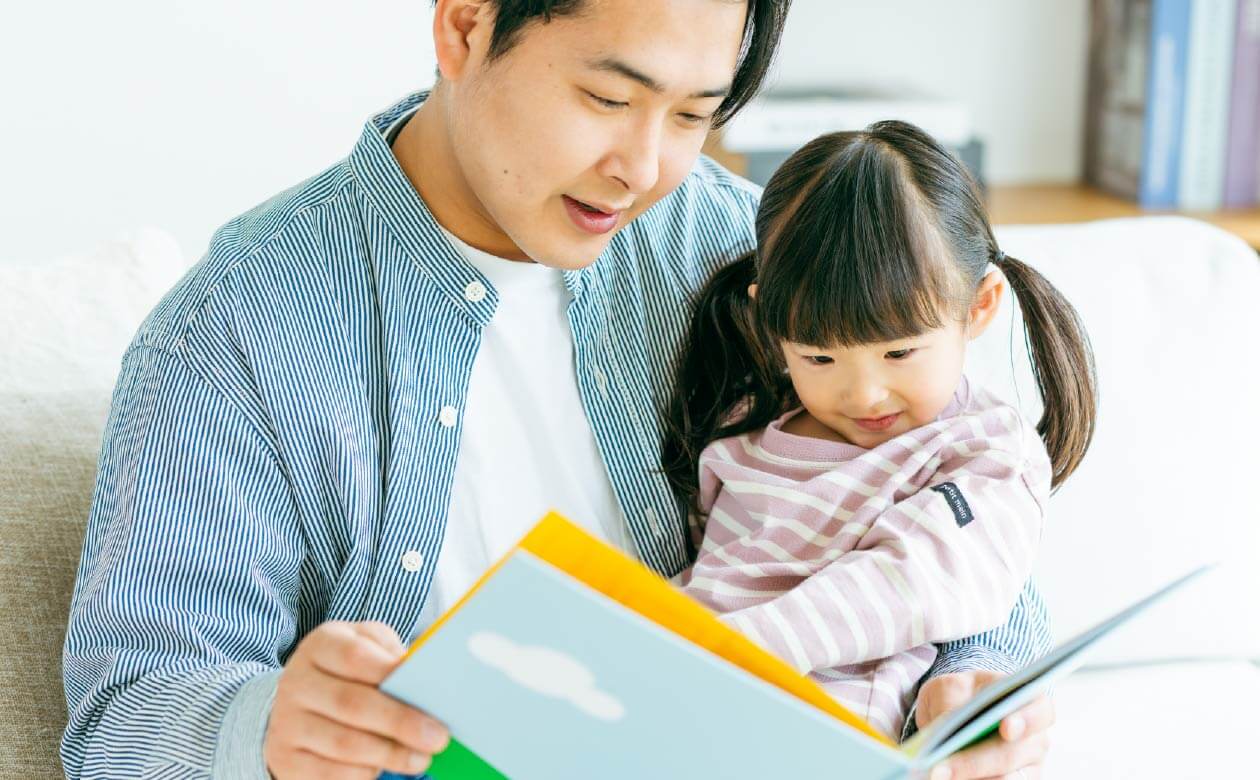 お父さんが娘に絵本を読み聞かせている